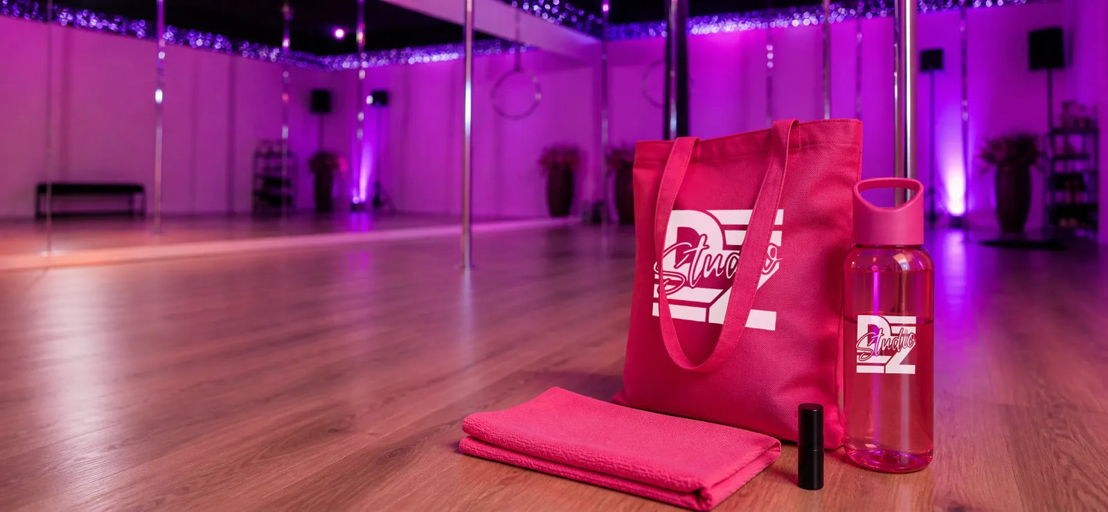 Bedrukte Studio DZ goodiebag met tas, drinkfles en sportdoekje in een roze verlichte dansstudio