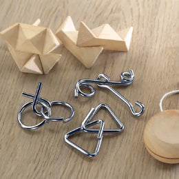 Drie metalen denkspelletjes naast houten puzzels op tafel, Zilver en bruin - 199191